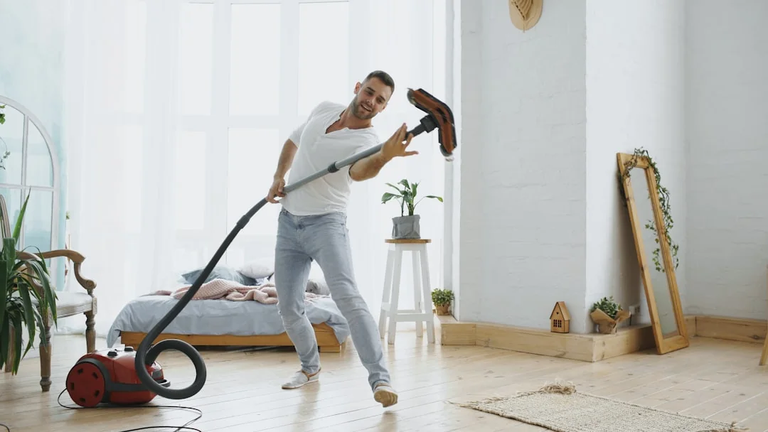 A professional cleaner in protective gear vacuuming the floor in a modern living room.
